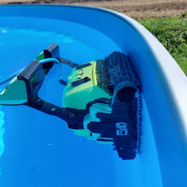 Robot piscina Dolphin Supreme M5 in azione lungo il bordo di una piscina naturale.