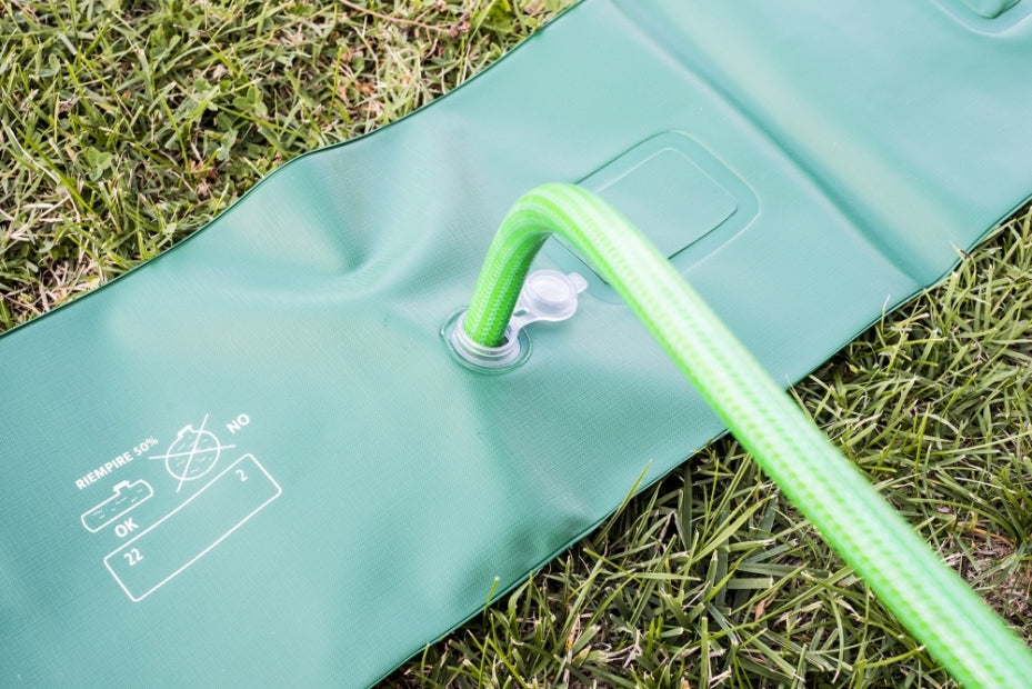 Tubolare in PVC verde su erba, con tubo di riempimento inserito in una valvola.