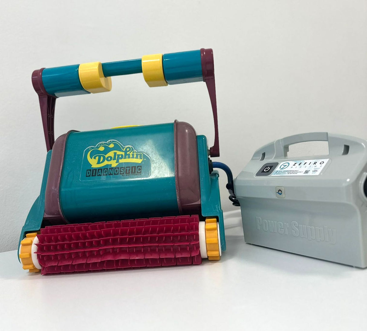 Robot piscina Dolphin Diagnostic 2001 Digital con alimentatore, su superficie bianca.