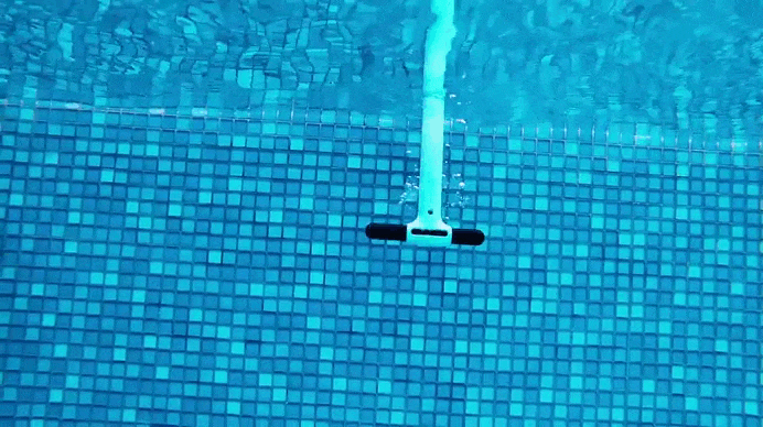Robot piscina Dolphin Eon 100i in azione sul fondo piastrellato di una piscina.
