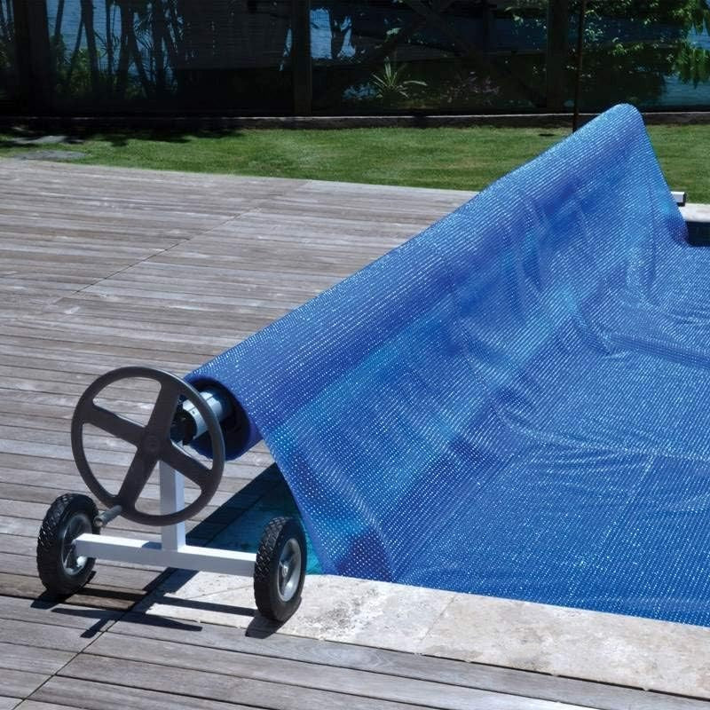 Rullo avvolgitore Kokido KALU con telo blu su bordo piscina in legno.