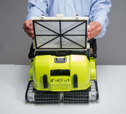 Robot piscina Dolphin Supreme M5 Bio-Suction, coperchio aperto, su tavolo bianco, operatore in camice azzurro.