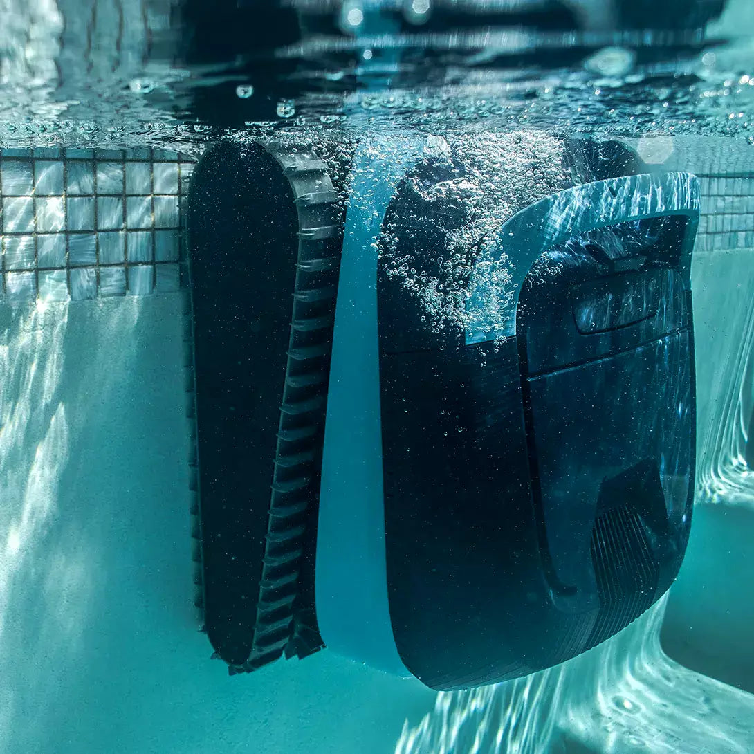 Robot piscina Dolphin Eon 100i in azione sott'acqua, adiacente a una parete piastrellata.