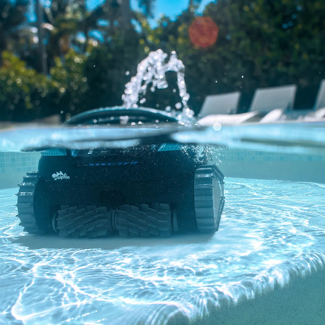 Robot piscina Dolphin Eon 100i in azione sott'acqua, bordo piscina visibile sullo sfondo.