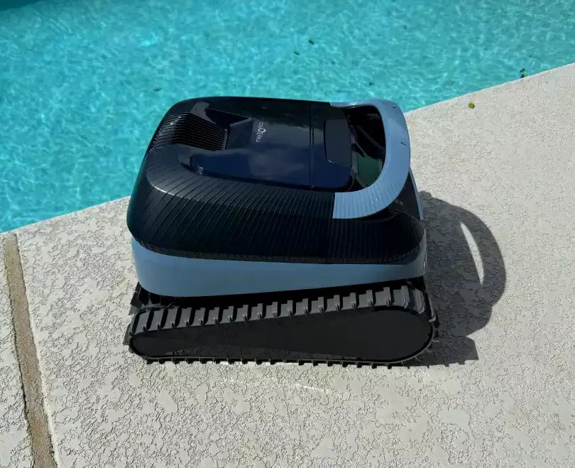 Robot piscina Dolphin Eon 100i sul bordo, design compatto e cingoli neri, vicino all'acqua azzurra.