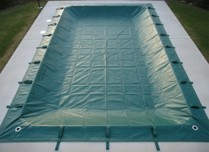 Telo di copertura invernale verde per piscina, con asole e bordatura rinforzata, su pavimentazione esterna.