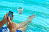 Rilevatore Ondilo ICO V2 galleggia in piscina, persona controlla parametri su smartphone.