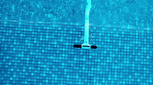 Robot piscina Dolphin Eon 100i in azione sul fondo piastrellato di una piscina.