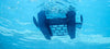 Robot piscina Dolphin Skimmi 300 in azione sott'acqua, vista dal basso, con sensori e alimentazione solare.