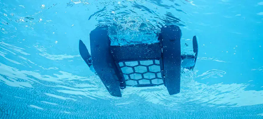 Robot piscina Dolphin Skimmi 300 in azione sott'acqua, vista dal basso, con sensori e alimentazione solare.