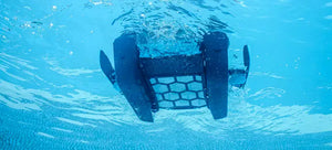 Robot piscina Dolphin Skimmi 300 in azione sott'acqua, vista dal basso, con sensori e alimentazione solare.