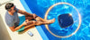 Robot piscina Dolphin Skimmi 300 galleggia in acqua vicino a una persona seduta a bordo piscina.