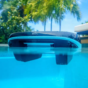 Robot piscina Dolphin Skimmi 300 galleggia in superficie, sfondo di palme e cielo blu.